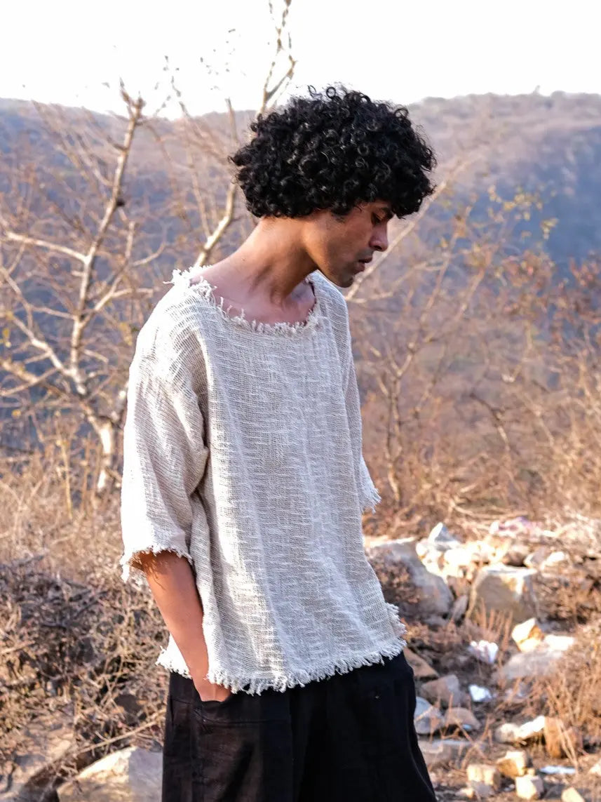 Natural cream jute T-shirt side view with one hand in a trouser pocket, open weave and frayed hem