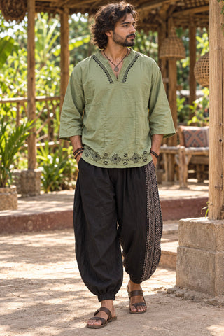 Full length green baggy kurta worn with black printed dhoti pants and leather sandals