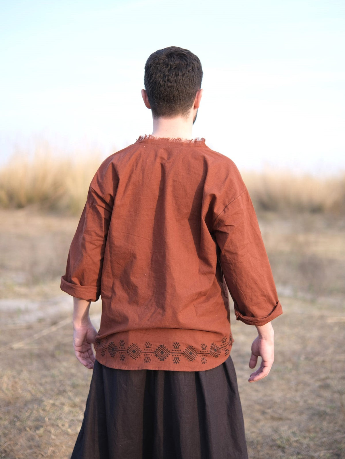 Back view of rust baggy kurta with tribal block print border above the hem