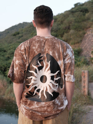 Back view of the Become the Light tee showing the black and cream celestial sun graphic with hand and eye motifs.