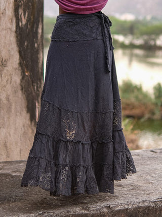 Black khadi wrap skirt seen from behind at the waist beside a river, lace waistband panel and tie cord in close view