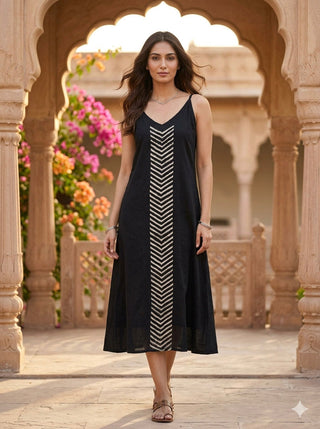 Black khadi cotton midi dress with beige chevron embroidery, worn front-facing in a Rajasthani archway