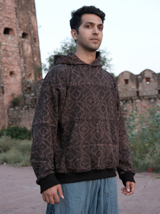 Black maze-print hoodie, angled front view on male model, sandstone fort courtyard