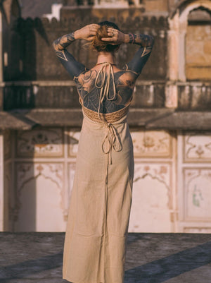Beige Devi Maxi Dress halter tie back view, hands in hair, heritage building