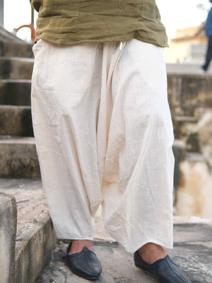 Natural cream harem pants from waist to ankle with an olive green tee, worn with black loafers on outdoor stone steps.