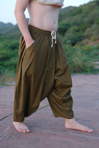Olive green harem pants worn full length with a hand resting at the side, white drawstring cords at the elasticated waist.