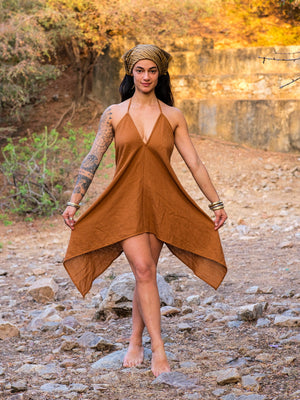 Model in a headscarf holding the Dumati Dress skirt out, front view of the asymmetric handkerchief hem in earthy brown cotton