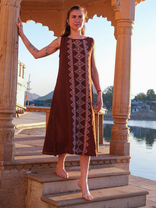 Ekakshi Maxi Dress in rust brown, model descending temple steps at dusk with a lake behind