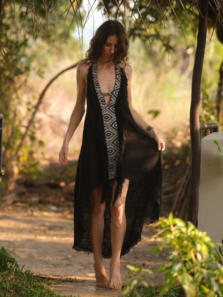Woman in black Elementos halter maxi dress with tribal panel, standing in a green garden, front view