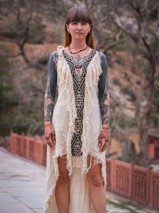 Close view of cream fringe maxi dress with navy tribal embroidery, arms raised