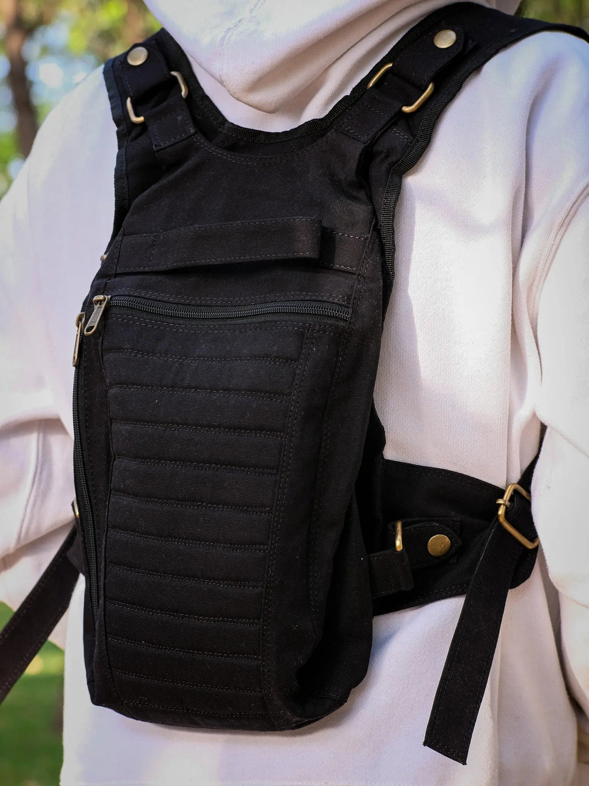 Close crop of the black Enigma Ninja Bag worn on the chest, horizontal stitching and zipper pulls in frame
