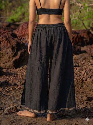 Fisherman wrap pants in black hand block print cotton, back view on beach rocks