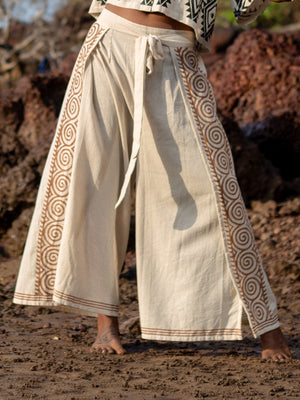 Fisherman wrap pants in natural cotton, full body front view on beach rocks