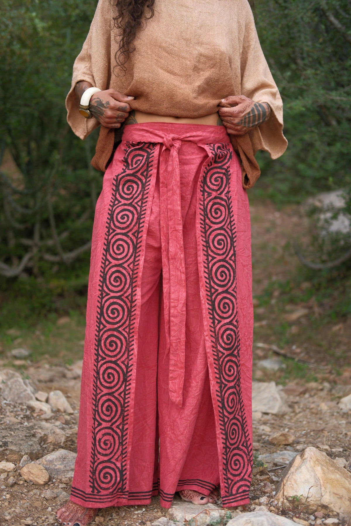 Fisherman wrap pants in red cotton, front full body view on a forest path