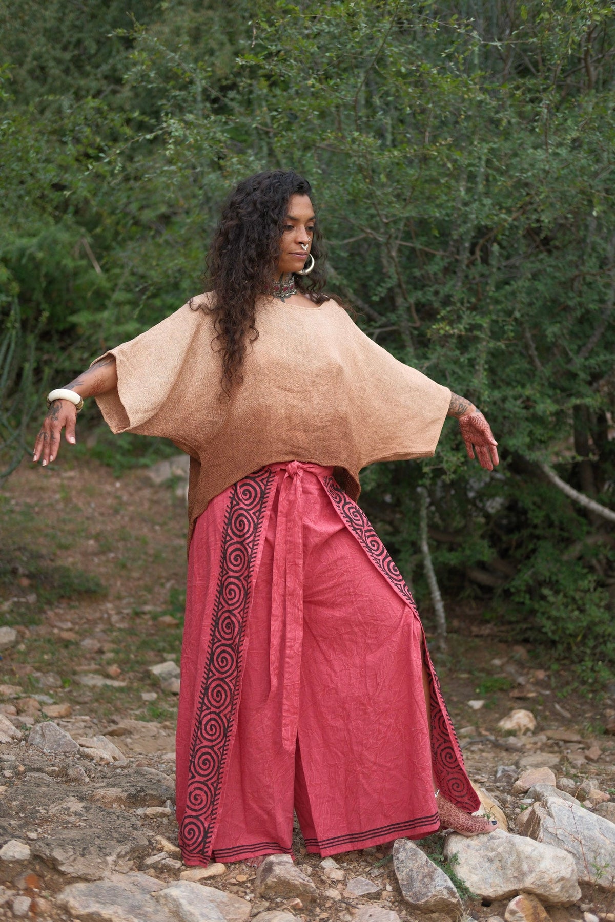 Fisherman wrap pants in red cotton, side full body view among trees
