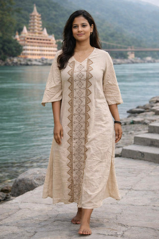 Model in the beige Garga Dress, a hand block print cotton maxi with a geometric centre panel, standing by a riverside temple