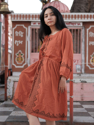 Gerua rust cotton dress for women worn before a pink Rajasthani temple in a knee-length A-line silhouette