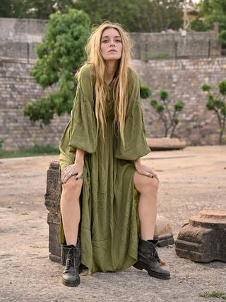 Green crepe maxi dress worn crouching on heritage stones at dusk