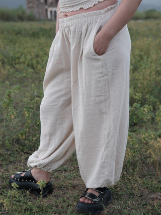 Close view of Hoor harem pants with a hand in the side pocket and a gathered ankle cuff above a black sandal