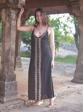Idhika Dress in black, front view of the free-size cotton maxi beside a garden pillar