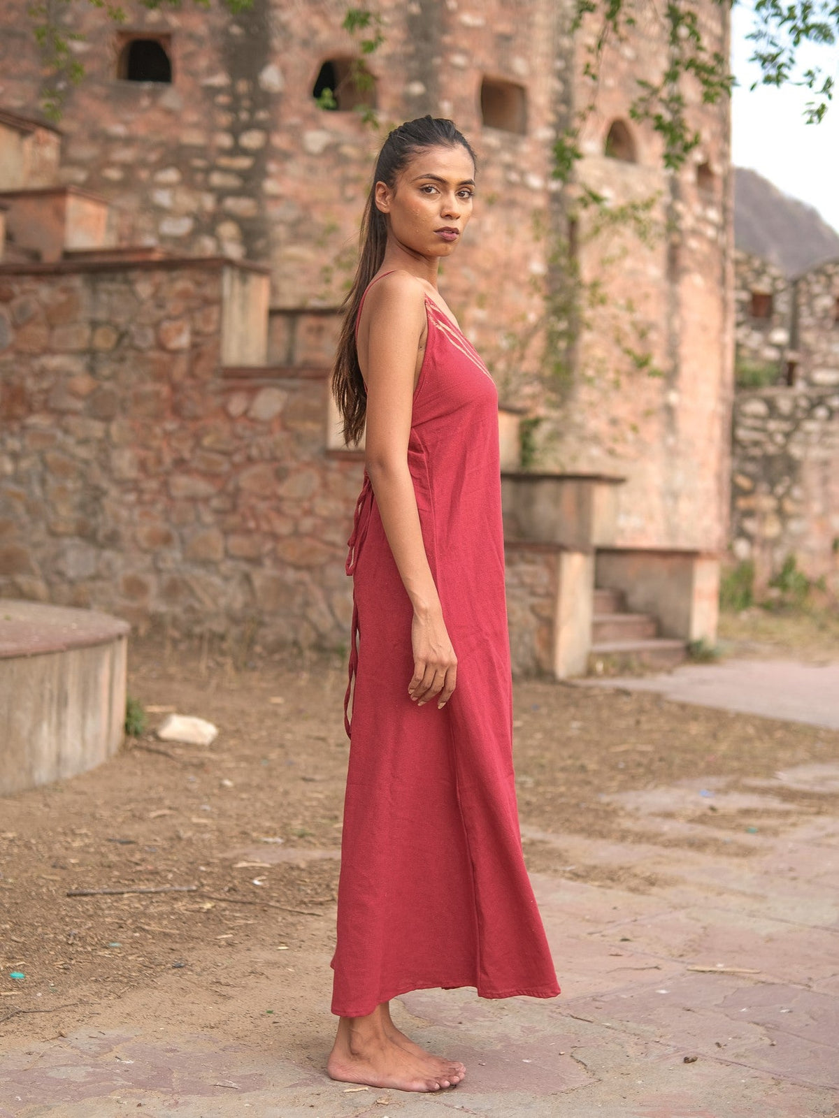 Idhika Dress in maroon, side view of the free-size cotton maxi among old ruins