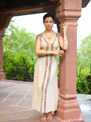 Idhika Dress in natural cream, front view of the block print cotton maxi beside a carved pillar