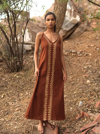 Idhika Dress in rust brown, front view of the free-size cotton maxi among dry desert trees