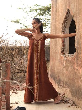 Idhika Dress in rust brown, front view of the block print cotton maxi at a haveli window