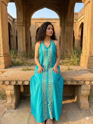 Idhika Dress in turquoise blue, seated view of the cotton block print maxi on a carved stone bench