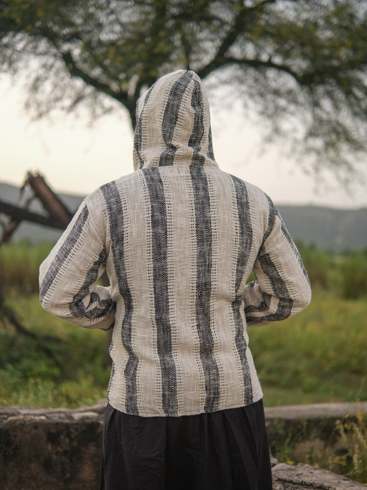 Back view of the striped hooded jacket with the hood raised, charcoal stripes running across the shoulders
