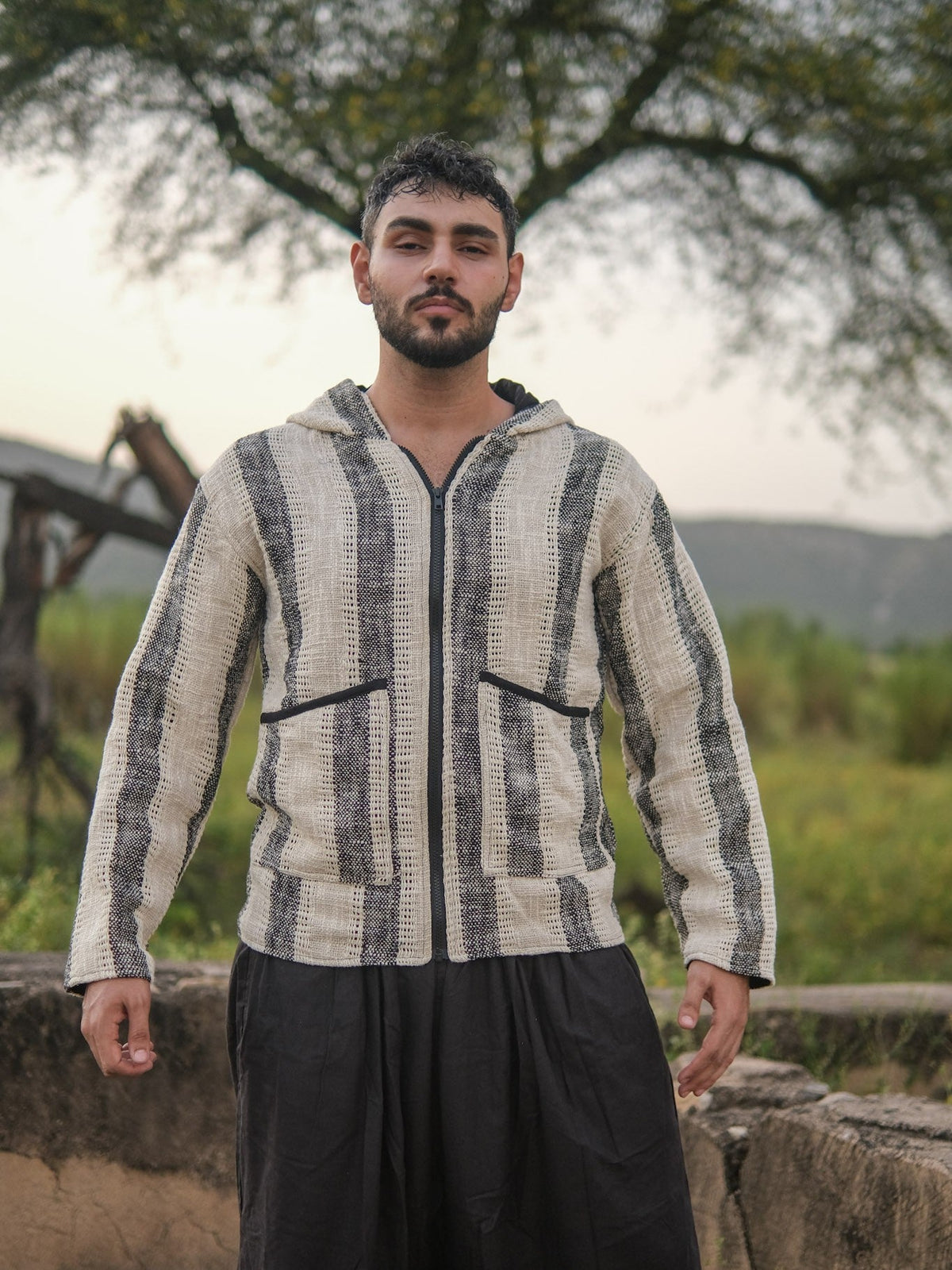 Front view of the striped hooded jacket in ivory and charcoal cotton, hood down, zip closed, on a male model