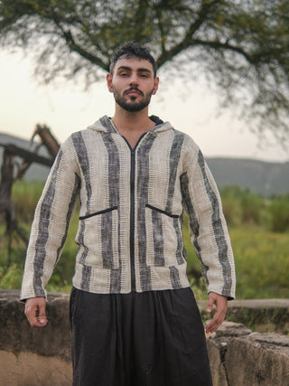 Front view of the striped hooded jacket in ivory and charcoal cotton, hood down, zip closed, on a male model