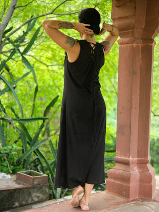 Laced back and sleeveless cut of the black Kashi Maxi Dress in a pillared corridor