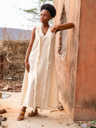 Kashi Maxi Dress in natural khadi cotton, model resting an arm on an ochre wall