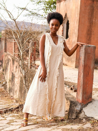 Natural cream Kashi Maxi Dress, front view with fringe trim in a heritage courtyard