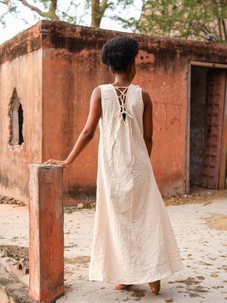 Laced back of the natural Kashi Maxi Dress, model walking past an ochre wall