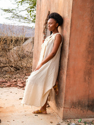 Natural cream Kashi Maxi Dress, model leaning against a sunlit ochre heritage wall