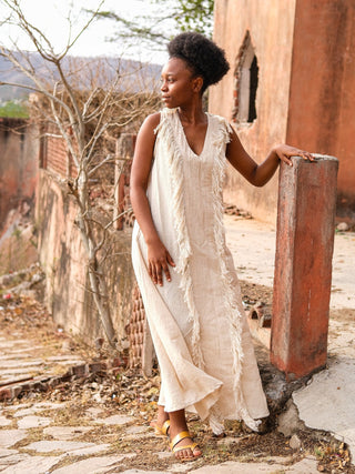 Natural Kashi Maxi Dress, sleeveless V-neck silhouette beside a weathered stone pillar