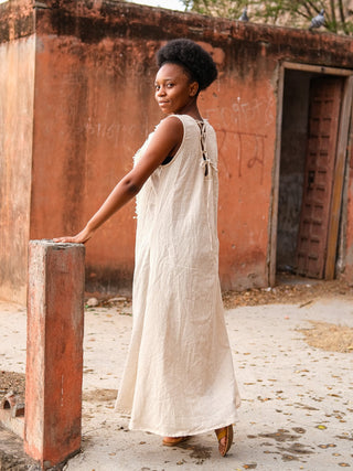 Kashi Maxi Dress in natural cotton, model turning back beside a stone pillar