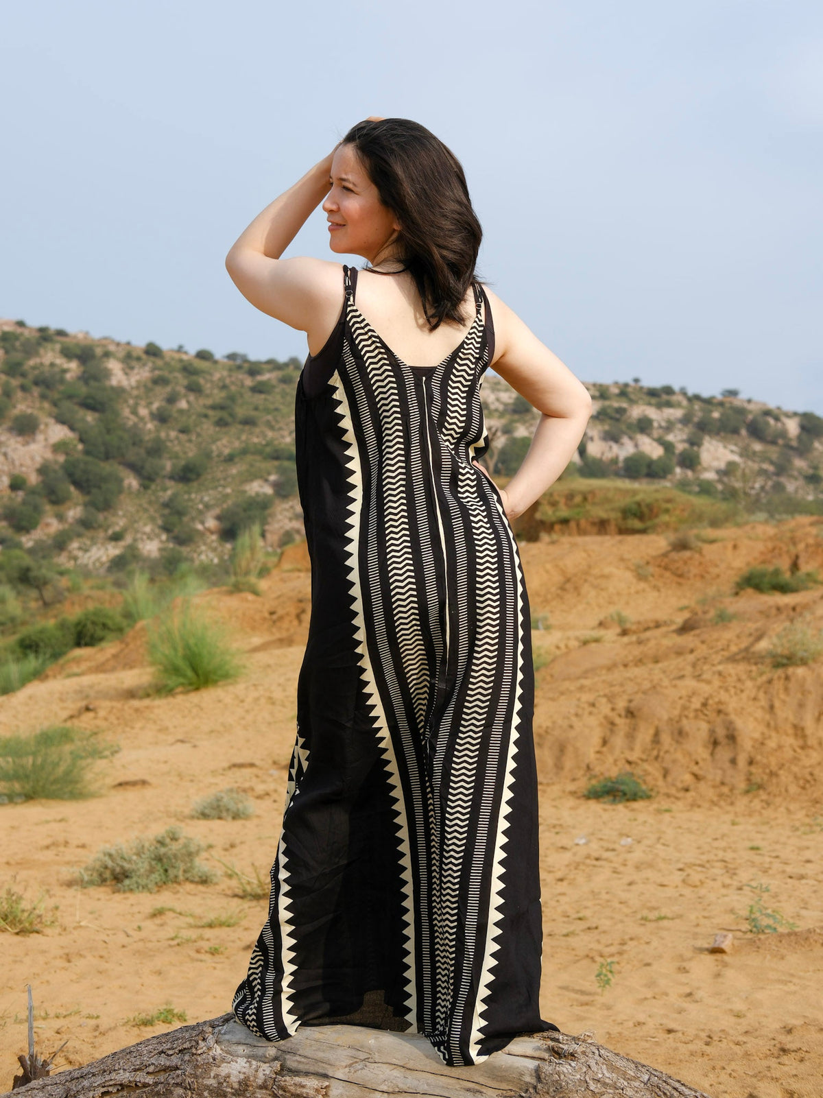 Full length back view of a handblock printed black and ivory khadi maxi dress worn in a desert landscape
