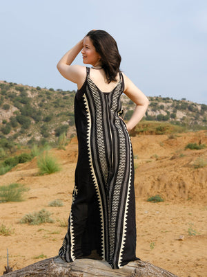 Full length back view of a handblock printed black and ivory khadi maxi dress worn in a desert landscape