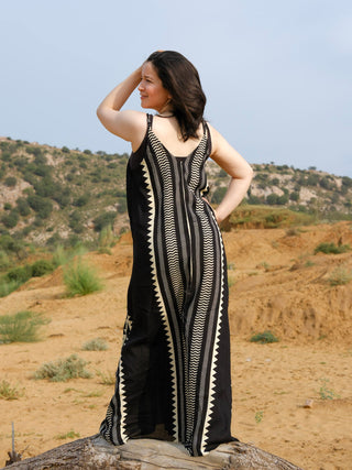 Full length back view of a handblock printed black and ivory khadi maxi dress worn in a desert landscape