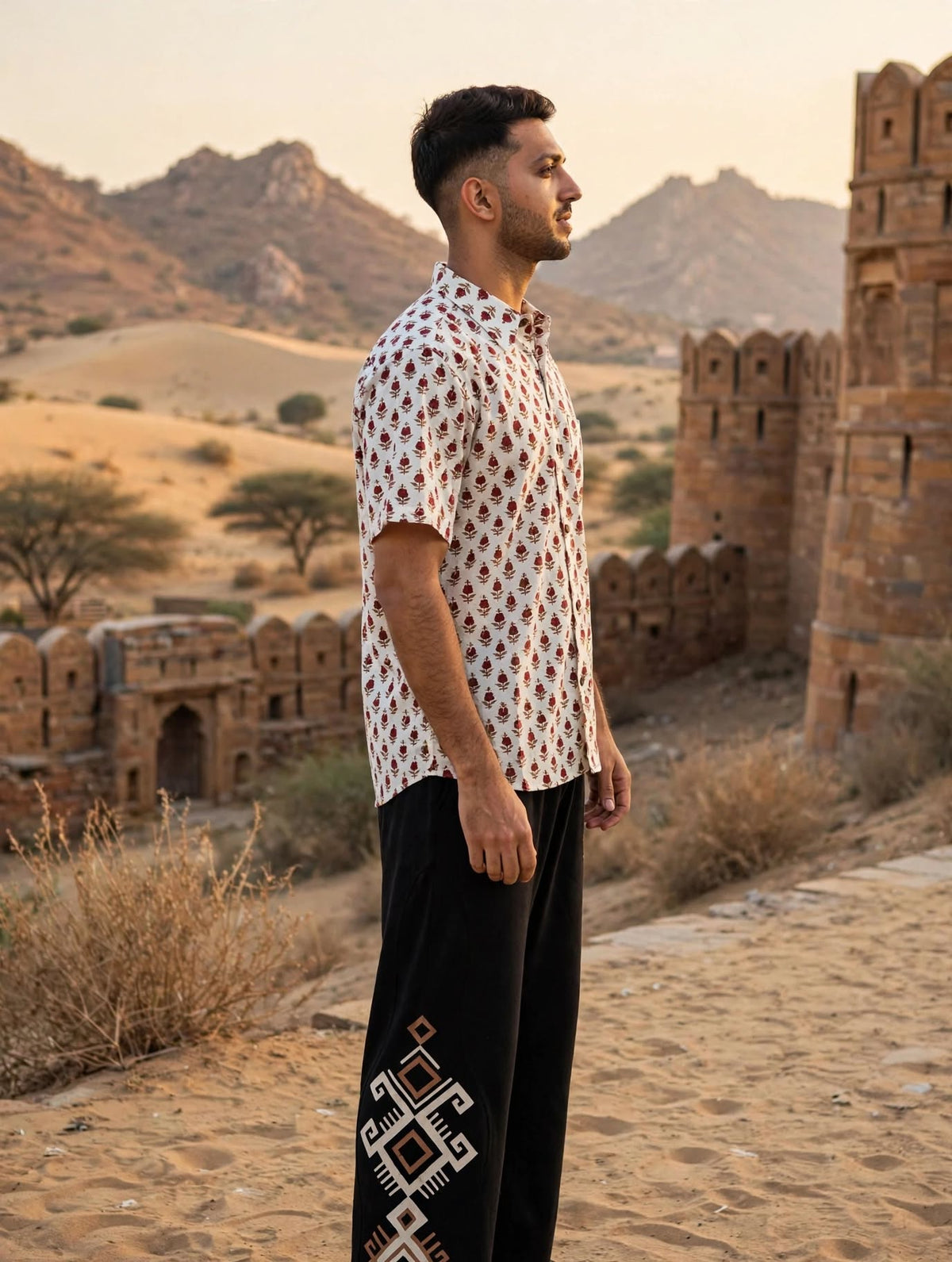 Phool floral shirt for men in profile against desert ramparts, small maroon and green flower print on off-white cotton
