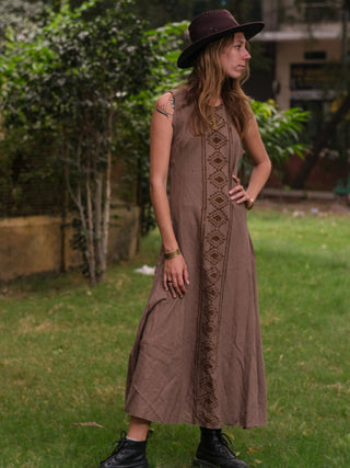 Woman in the brown Mojo block print cotton maxi dress and a wide brim hat standing in a green garden