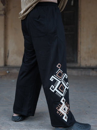 Back view of black Naqsh trousers showing a patch back pocket and the geometric print edging the wide leg