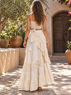 Back view of the natural cream khadi wrap skirt on a paved courtyard, lace tiers falling to the ankles