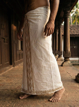 Side view of the Natural Ory Dhoti showing the brown diamond border print on soft cotton, worn on a heritage stone floor