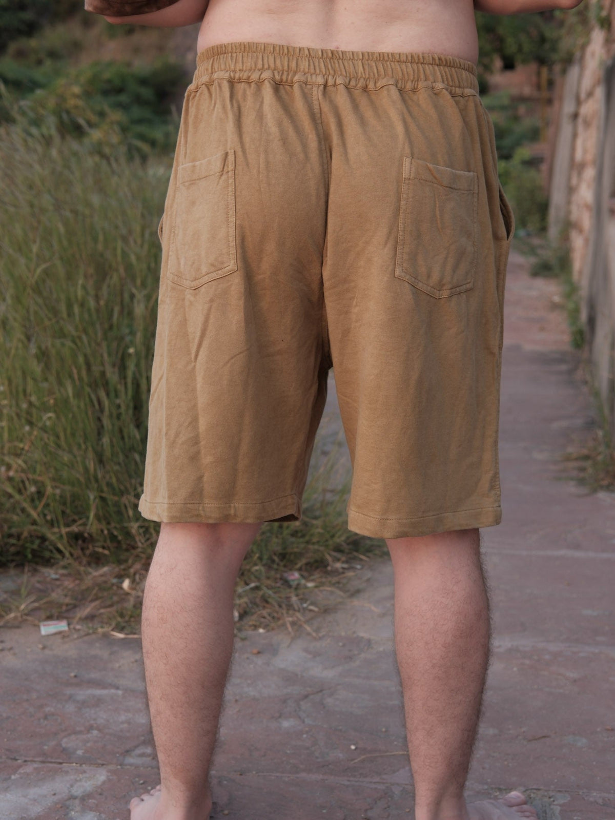 Back view of the Nimit Shorts in mustard tan cotton, showing the elastic waist and back patch pockets