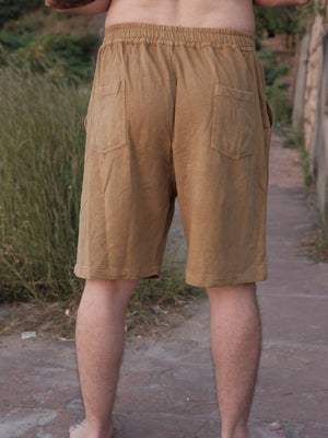 Back view of the Nimit Shorts in mustard tan cotton, showing the elastic waist and back patch pockets