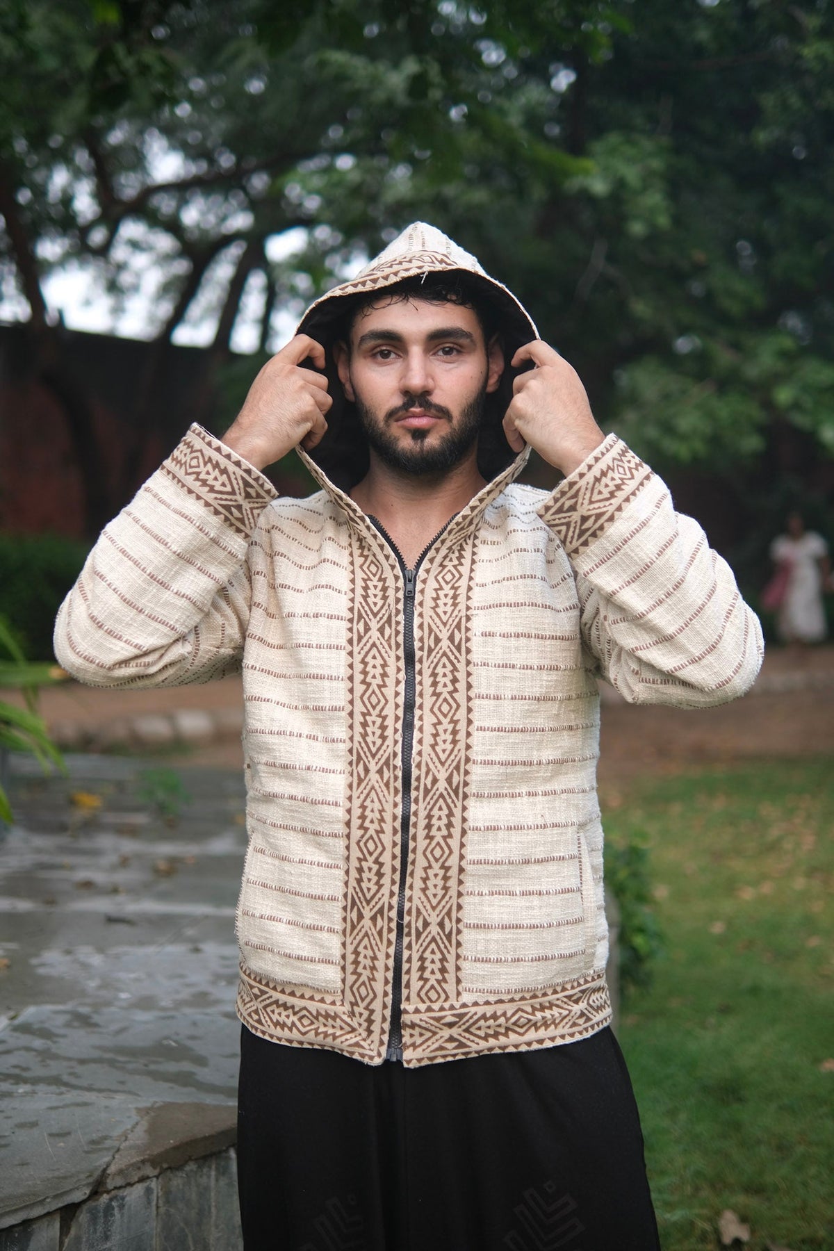 Nomad hoodie held open at the shoulders, geometric print placket, front zip and a vertical pocket slit